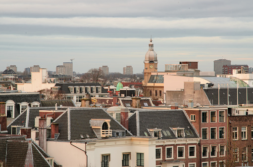 A photo taken from the roof of a building, looking out over a busy city with a clock tower visible in the distance.