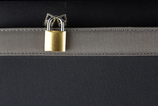 Small brass padlock securing a bzippered suitcase compartment