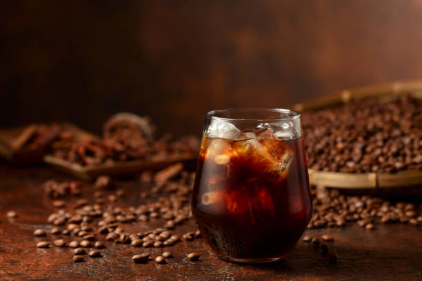 Black iced coffee with coffee beans on a brown vintage table. Black iced coffee with coffee beans on a brown vintage table. Copy space. cafe transparent glass table stock pictures, royalty-free photos & images
