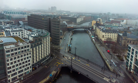 Awe Drone view on Weidendammer Brucke (bridge) and Bahnhof of Berlin-Fridrichstrasse and bridge  over Spree river.People walking in distance. In right upper corner Glass Dome of Reichstag building