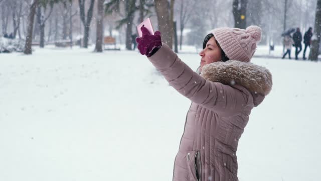 Young Woman Taking Selfies In A Snowy Park In Winter