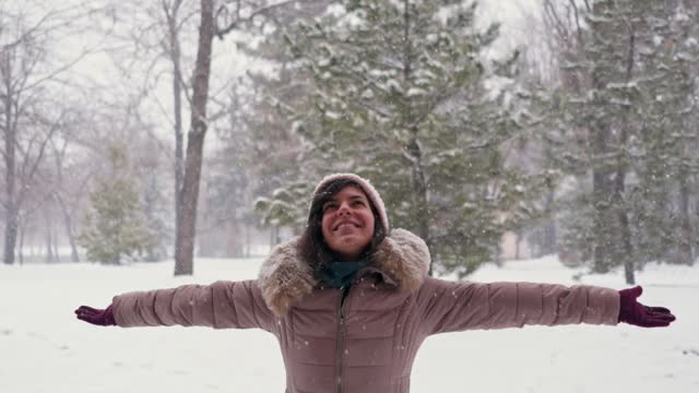 Young Woman With Arms Outstretched Enjoying Snowy Day In A Park In Winter