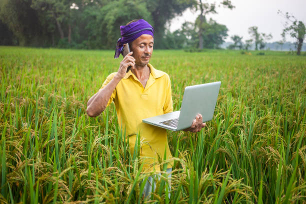 istock modern farmer using mobile phone and laptop while standing in the crop field and talking on phone 2148752467