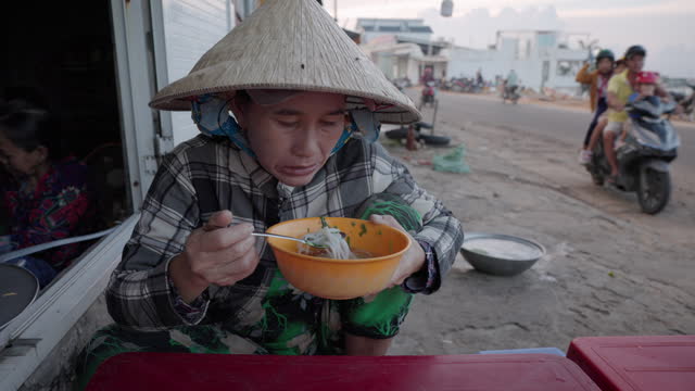 Vietnamese woman eating a pho bo, South Vietnam