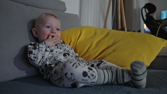 Cute Toddler Boy Relaxing On Sofa And Watching TV