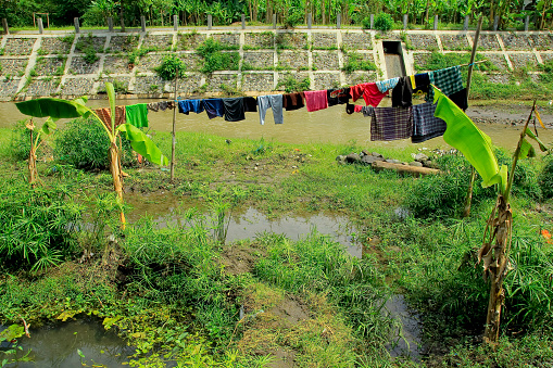 Bukit Lawang, Sumatra, Indonesia - January 19th 2024:  People washing both clothes and themselves in the river in the middle of the village