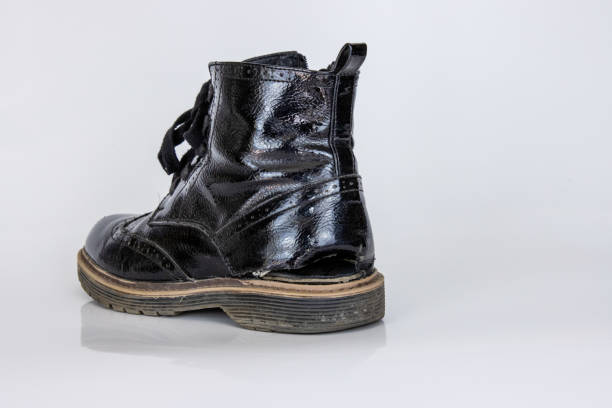 Side view of one very worn boot. Old used broken Black Leather lace high boot. Trendy ankle shoe. Stylish womens mens unisex Grunge boot with bootlace. isolated on white background