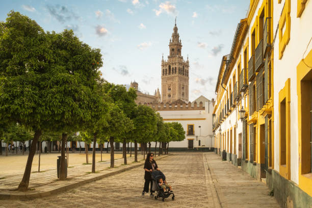 A mother is visiting Seville with her child. La Giralda tower in the background.