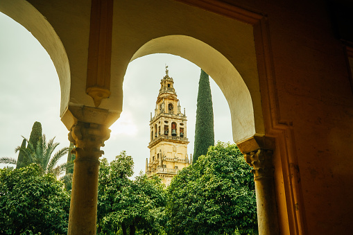 Seville, Spain - September 19, 2018: Looking through an archway back along a covered elevated viewing gallery in the  Alcazar gardens of Seville. The Alcazar, which dates back to the 12th century, forms part of a UNESCO World Heritage site.