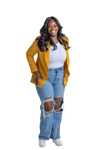 Full length portrait of a full figured black woman with long hair, ripped jeans and a yellow jacket