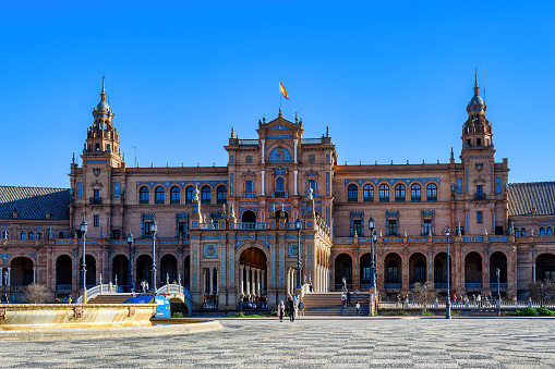 Seville, Spain - March 12, 2024: Exterior facade and tourists in the national landmark building Plaza de Espana. The square and the building are major tourist attractions in the city