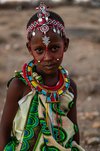 African little girl from Samburu tribe carrying water to the village, African women and children often walk long distances to bring back jugs of water that they carry on their back.  Samburu tribe is north-central Kenya, and they are related to  the Maasai.
