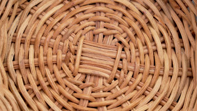Textured pattern of empty handcraft rattan wicker bowl close up. Top view. Rotation