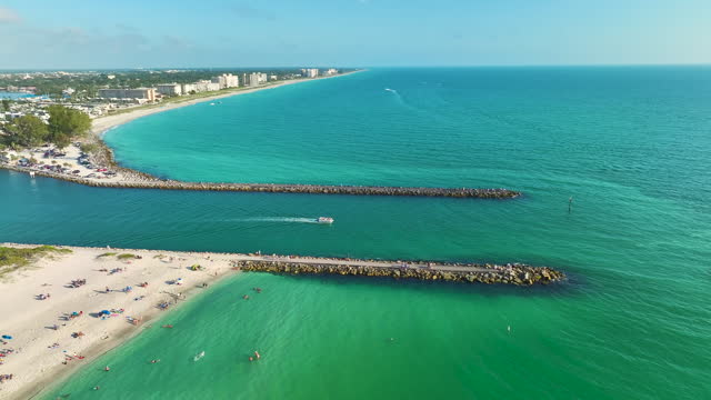 Rock jetty barrier and boats sailing at harbor on colorful ocean water near Venice and Nokomis beach in Sarasota County, USA