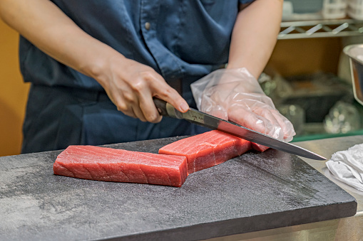 Skillful vendor cutting prime tuna fillets.