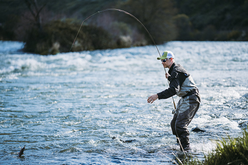 A fly-fisherman casting double-handed Spey rod in warm afternoon light.