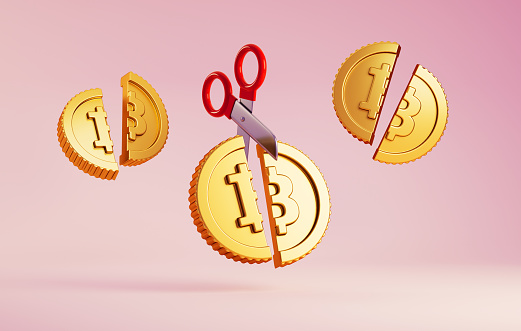 Cartoon Bitcoin coins cut in half by scissors on a colored background, concept of Halving, an event that occurs every four years and divides miners' rewards in half