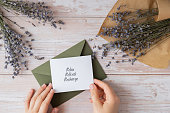 RELAX REFRESH RECHARGE text on supportive message paper note reminder from green envelope. Flat lay composition dry lavender flowers. Concept of inner happiness, slowing-down digital detox personal fulfillment