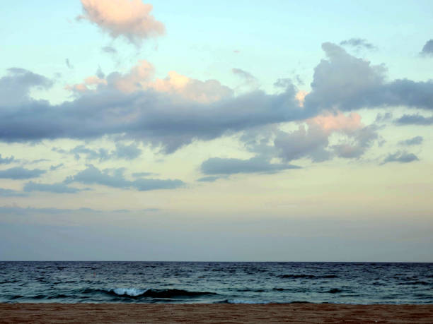 Lonely afro man with protective face mask sitting on a lounge chair on an empty beach