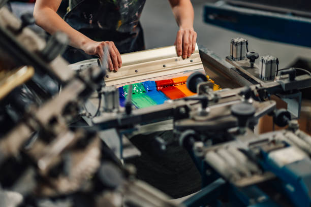 istock Close up of graphic worker's hands screen printing with squeegee. 2148765781