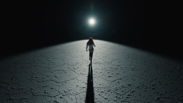 Salt Flats of Bolivia and a redhead dancer walking towards light at night