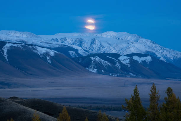 amazing sunset panorama over snowy mountain range with big glaciers with red, orange, violet and moonlight colors