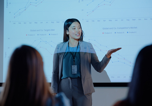Woman, finance and workshop with presentation for chart for stats, growth and stock market with audience. Person, presenter and financial advisor with board, speech or projector overlay at trade show