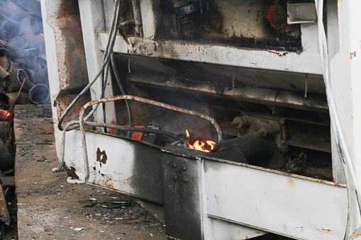 A large, unusable piece of metal is cut using the fire of a gas torch.