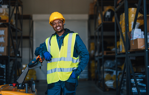 Smiling Warehouse Worker in Safety Gear Handling Equipment