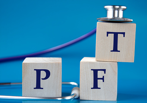 PFT (Pulmonary function test) - acronym on wooden large cubes on blue background with stethoscope