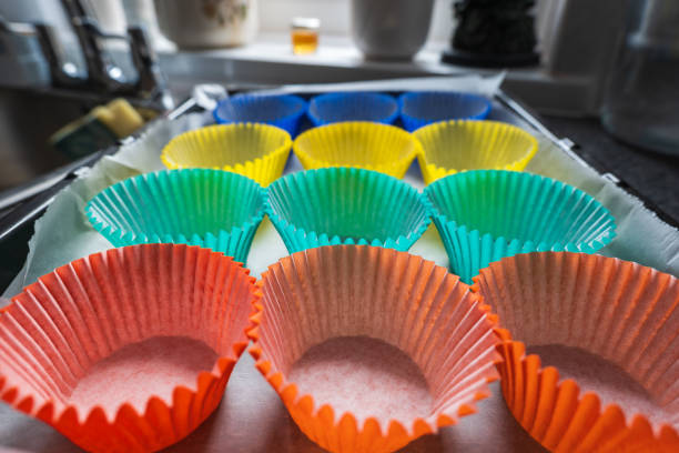A vibrant display of baking cups in shades of green, light blue, and electric blue, resembling an artful circle of colorful organisms. Perfect for creating sweet treats with a unique touch