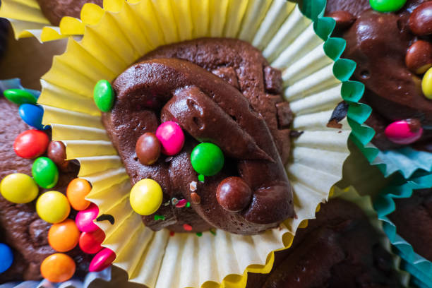 istock Homemade chocolate cupcakes with chocolate chips and colorful sweets sitting inside colorful baking liners 2148772133
