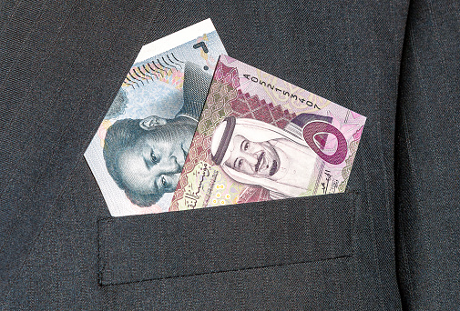 Saudi Arabia banknote with King Salman and Chinese yuan banknote with Mao Zedong in businessman suit pocket. Business concept photo of the exchange rate, stock exchange, trading