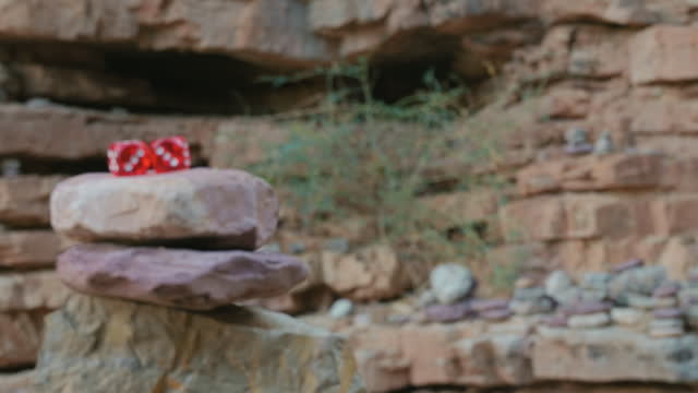 Two red dice are sitting on top of a rock
