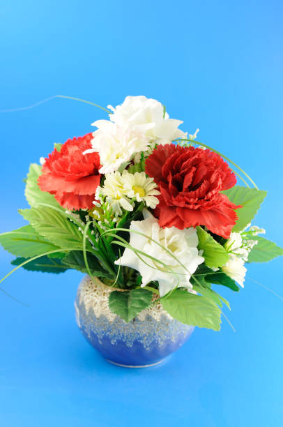 Artificial Flowers in a Vase Isolated on Blue Background