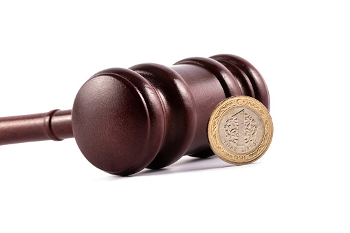 Wooden judge's gavel and 1 Turkish lira coin on a white background