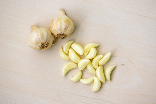 Fresh raw garlic cloves and whole garlic isolated on a wooden textured background. Top view