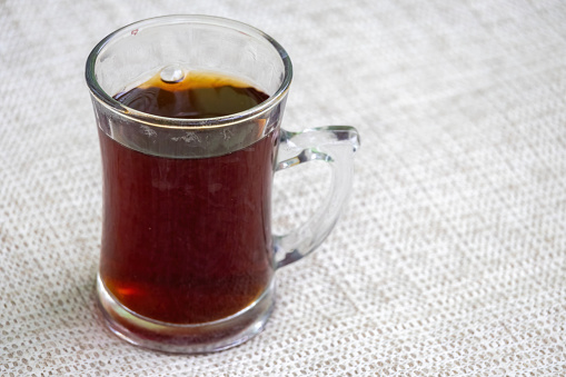 Black tea or red tea in a glass cup on white textured background. In Bangladesh, this is called Rong Cha or Lal Cha. Black tea is good for health.