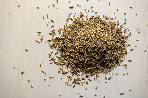 Cumin seeds pile on wooden background. Locally in Bangladesh, it is called Jeera. Cumin seeds are used in traditional medicine and as a spice in cooking food. Top view.