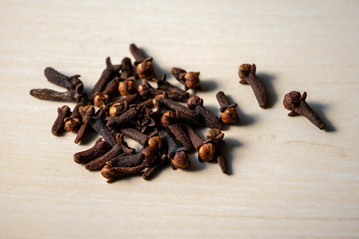 A pile of aromatic dry cloves on a wooden background. Locally in Bangladesh, it is called Lobongo.