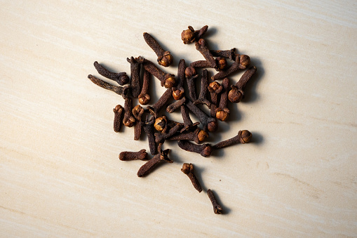 A pile of aromatic dry cloves (Syzygium aromaticum) on a wooden background. Locally in Bangladesh, it is called Lobongo. Top view.