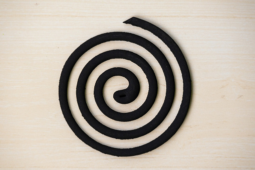 Mosquito repellent coil isolated on wooden background. The coil's active ingredient evaporates with the smoke, which helps to repel or kill mosquitoes.