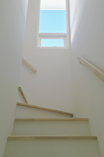 Home interior image of minimal design winder staircase with vertical widow, clear glass and vertical blinds for modern small space housing project.
