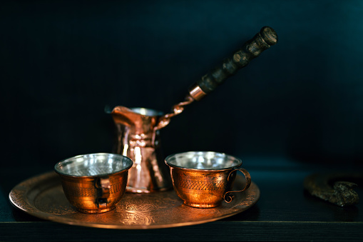 Handmade coffee pot and cups on a copper plate.