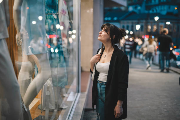 istock Young woman looking at shop window at night. 2148784060