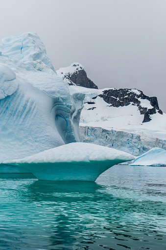 An Antarctic landscape shot near Cuverville island, highlighting mountains and icebergs.