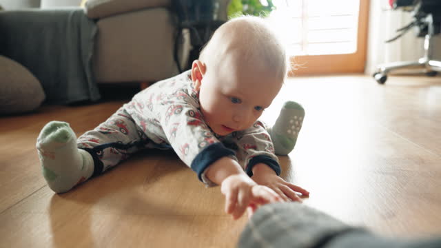 Cute Baby Boy On Hardwood Floor Reaching For Cushion