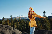 Woman smile with teeth happiness and laughter hiker in yellow raincoat put her hands up and jumping trip in the fall and hiking in the mountains in the sunset freedom