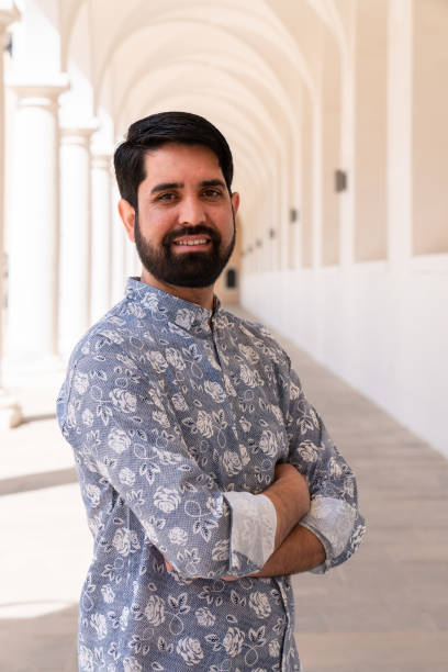 istock A modern, stylish Pakistani man with a dark beard and light clothes stands among white columns 2148786824