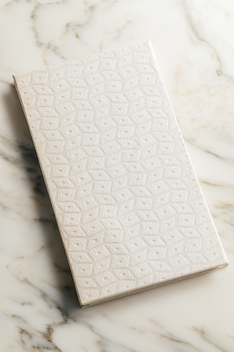 pearlescent geometric pattern paper cover of book on white marble